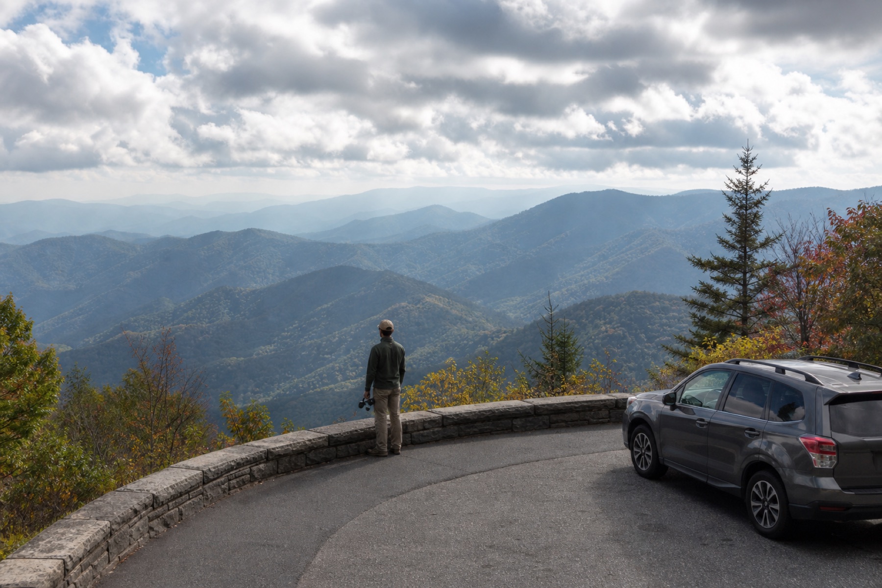 A traveler viewing layered ridges from a Great Smoky Mountains overlook